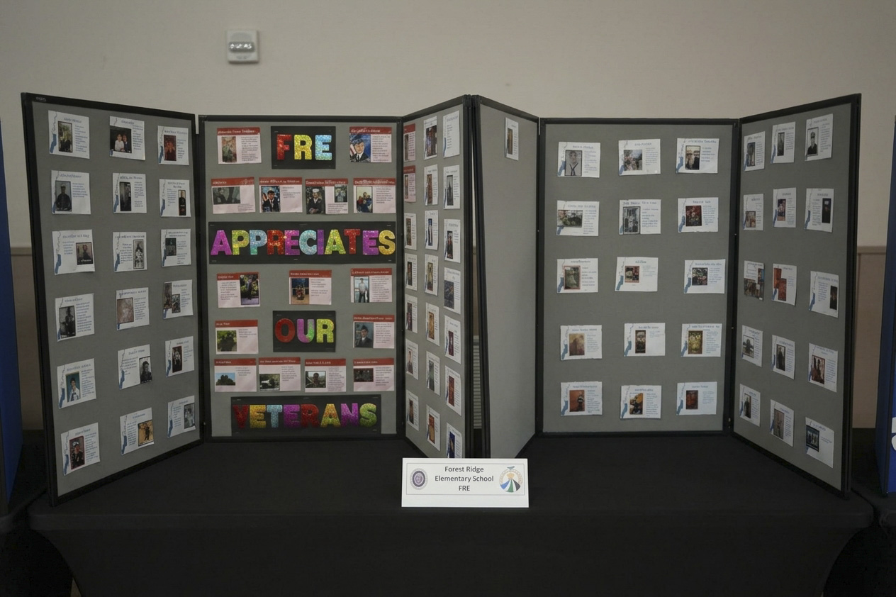 A large multi-panel display board covered in small photos and cards stands on a black-draped table.